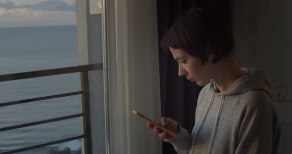 Side Portrait of Young Millennial Girl Using Smartphone Reading News alt