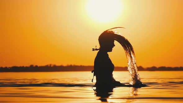 Silhouette of Woman Flipping Her Long Hair Back in Water. Slow Motion 240 Fps alt