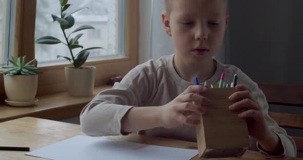 Front View of Child Kid Choosing Pencil for Homework Sitting By Window Natural Light