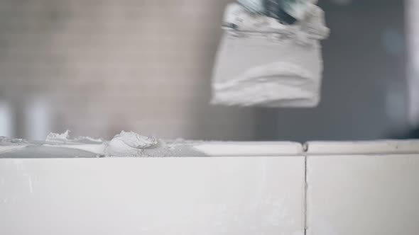 Man Hand in Gloves Holds Small Putty Knife and Smears Wall alt