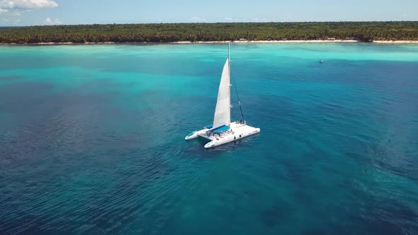 drone shoot of the catamaran in the saona island in the caribbean sea with blue water in a sunny day alt