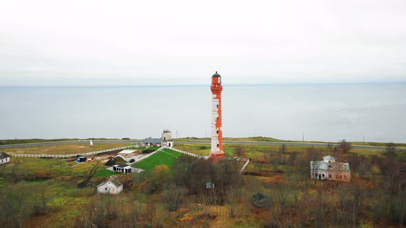 Beautiful Aerial Panning Shot of Scenic Old Lighthouse and Buildings on Picturesque Overcast Sea alt