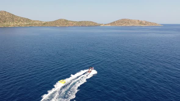 Aerial View of a Motor Boat Towing a Tube. Elounda, Crete, Greece