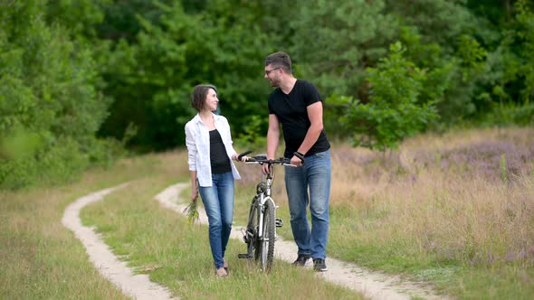 Young happy couple walking holding bicycles in the park