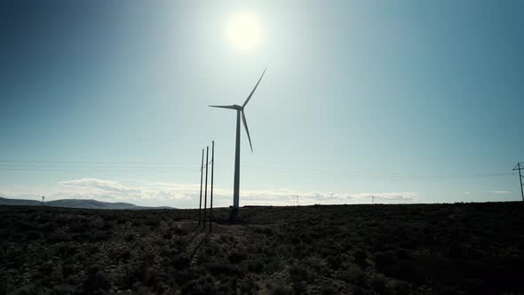 Backlit silhouette of a giant electric wind generator, carbon neutral energy, aerial orbit alt