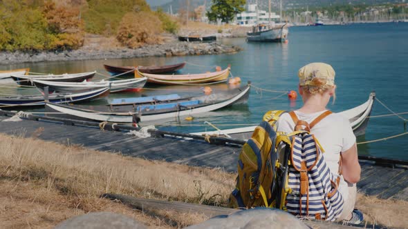 Woman Tourist with Bags Resting on the Beach Overlooking the City of Oslo alt