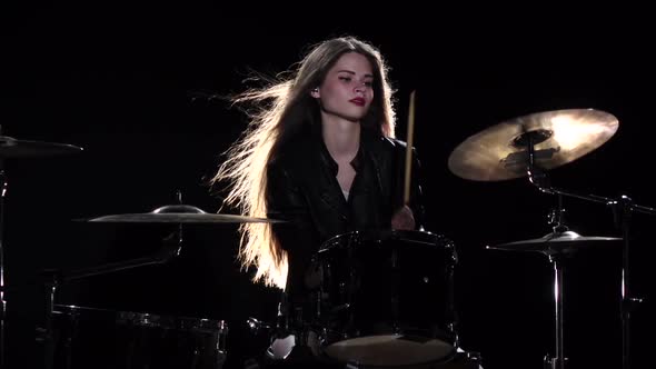 Drummer Girl Starts Playing Energetic Music, She Smiles. Black Background. Slow Motion alt