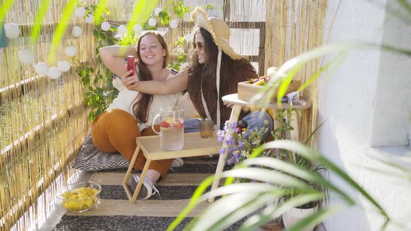 Ladies Make Selfie Sitting at Table with Lemonade on Terrace