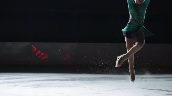 The Girl Skater Performs a Jump with the Rotation of a Triple Toe Loop in a Counter Light on an Ice alt