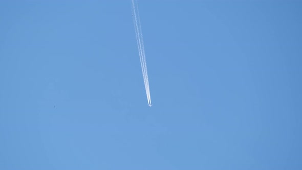 Distant Passenger Jet Plane Flying on High Altitude on Clear Blue Sky Leaving White Smoke Trace of alt