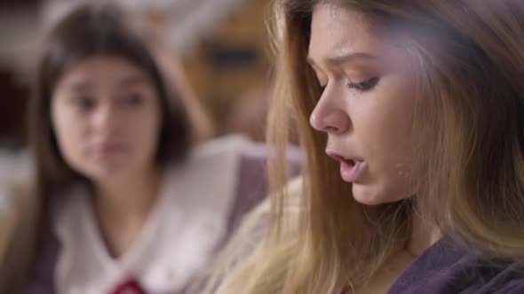 Side View Closeup Sad Beautiful Woman Talking Arguing with Blurred Friend at Background alt