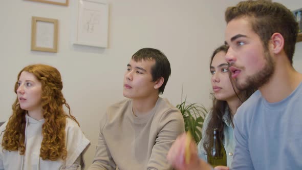 Sports Fans Eating Crisps and Watching Football Match on TV alt