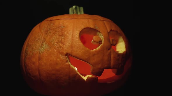 Rotation of an orange pumpkin with red candle and scary smile. Halloween concept