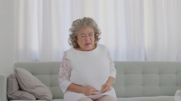 Asian Elderly senior woman with white hairs have a stomachache and uti or bladder pain alt