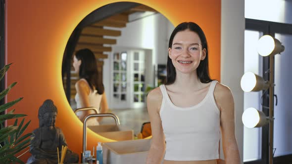 Young Woman with Dental Braces and Vitiligo Pigmentation Smiling to Camera Standing Near Mirror at alt