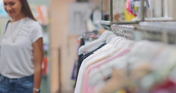 Girl Takes a Hanger with Clothes From a Shop Window of a Shopping Center