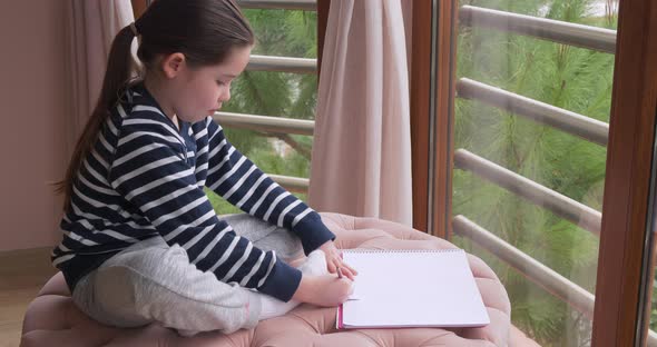 A Little Girl Drawing with Pencils at Home