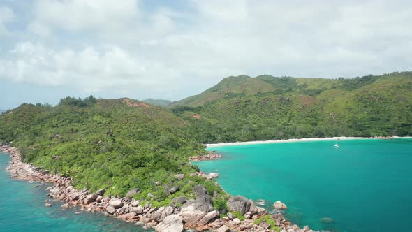 Aerial dolly over granite coast cape Anse Lazio toward to Petite beach alt