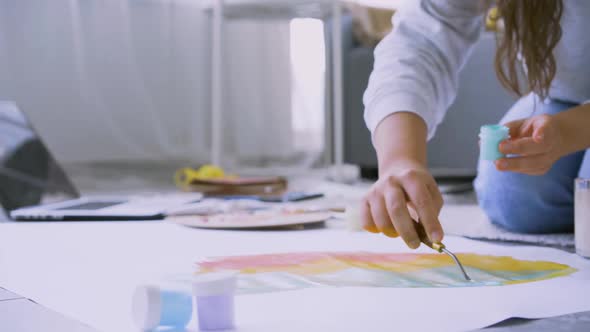 Woman Takes Paint From Jar to Draw Painting