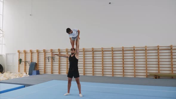 Athlete is Making a Handstand with One Hand on the Head of Partner Steadicam