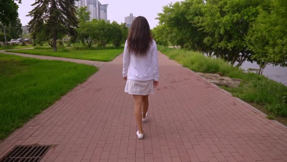 Back View Female Walks on the Street alt
