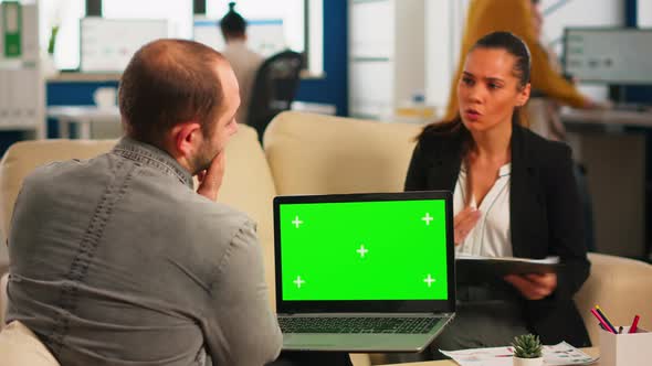 Business Team Sitting on Couch Analysing Graphs Holding Laptop with Mockup alt