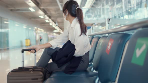 Asian business girl walk with luggage sitting in bench wait and look partner for flight at airport.