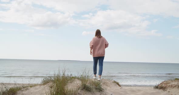Young Hipster Woman Standing on Top of the Hill Rising Hands Against the Sea