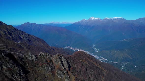 Stunning Bird's Eye View on the Rosa Khutor Village Drowning in the Forested Valley Among Majestic