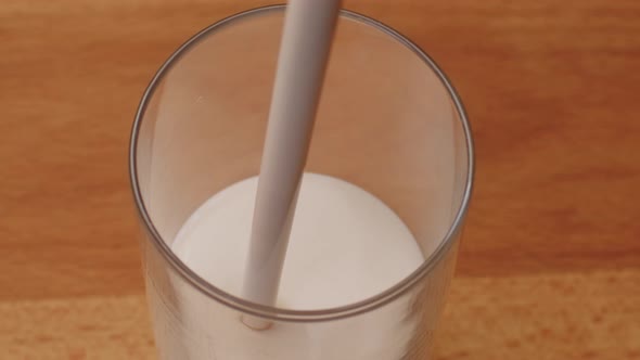 Yoghurt Pouring Into a Glass and Brim Over the Edgeon Table Close Up