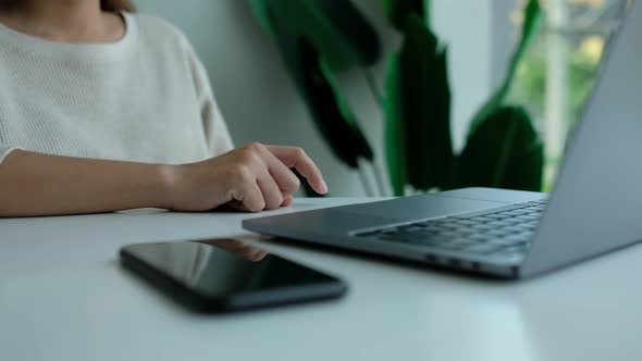 a business woman tapping fingers while working on laptop computer in office