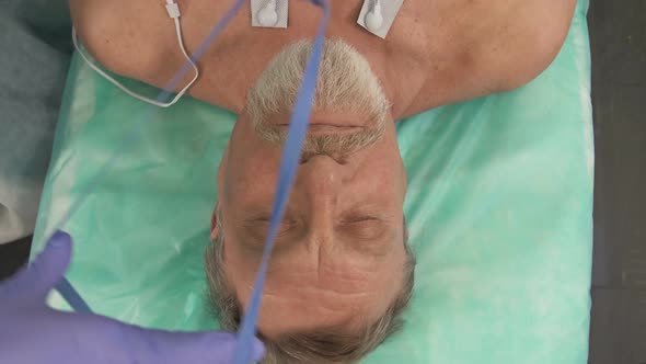 Doctor or Nurse Puts an Oxygen Mask on an Elderly Patient in a Hospital alt