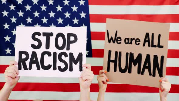 Protesters Hold Banners with Slogans - Stop Racism. We Are ALL HUMAN - Against Background of the USA alt