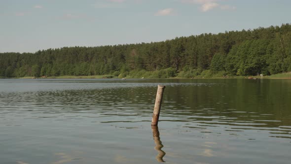 Reflections Through Calm Water Of Jezioro Glebokie Lake During Daytime In Poland. Pan Left Shot alt