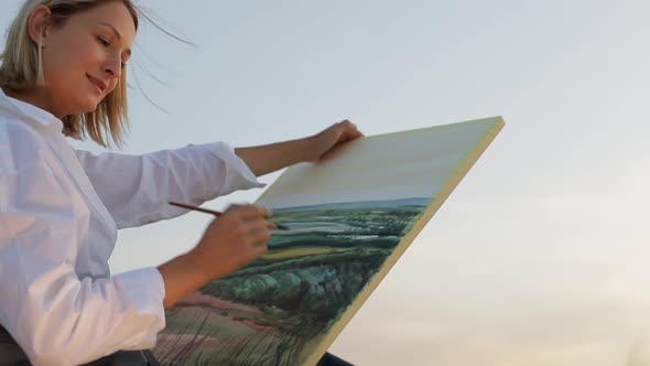 Young girl artist who paints a picture of nature. alt