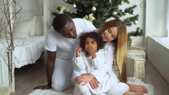 Young Happy Multi-ethnic Family of Mother, Father and Little Daughter Dressed in White at Background alt