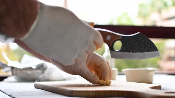 Chef Cuts Garlic on a Cutting Board with a Knife