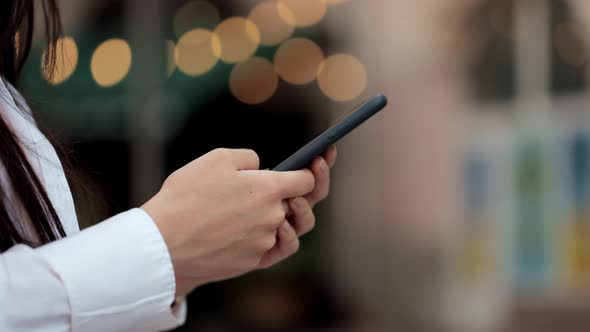 Close Up View Woman Hand Holding Smartphone Standing at the Street alt