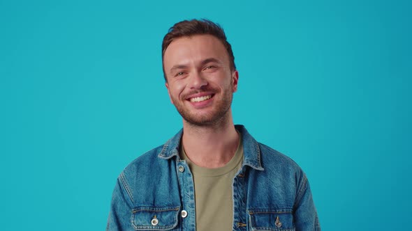 Young Caucasian Man Smiling Against Blue Studio Background