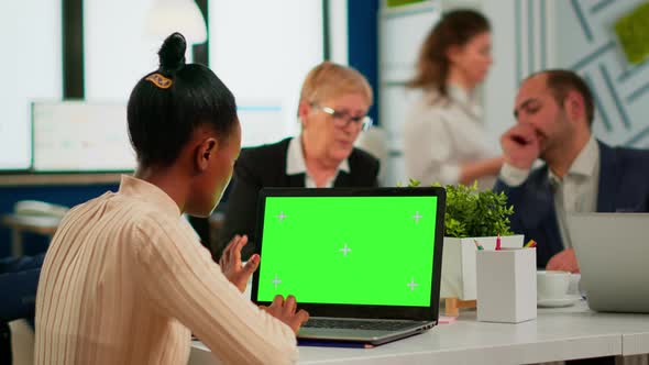 African Manager Woman Sitting at Conference Desk Looking at Laptop with Green Screen alt