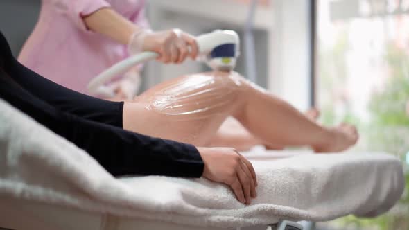 Beautician Doing Laser Hair Removal on Slim Legs Beautiful Woman in Beauty Salon alt