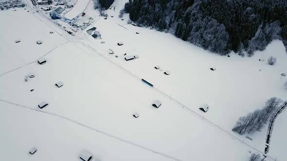 Aerial following a train going through Grainau town in a snowy winter. Bavaria, Germany. alt