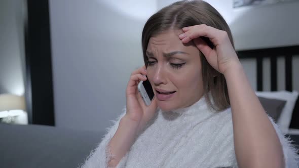 Crying Woman Talking on Phone While Sitting on Couch alt