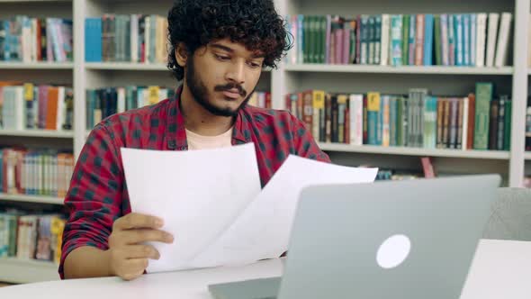 Sad Confused Indian or Arabian Male University Student in a Stylish Shirt Sits at a Table in the alt