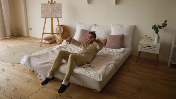 The man falls on the bed after a hard day, wants to relax alt