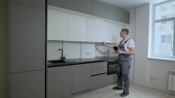 The Builder Checks the Quality of the Installation of Kitchen Furniture Construction alt