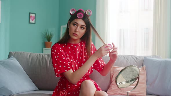 Woman Is Putting Hair Curler and Looks at Camera alt