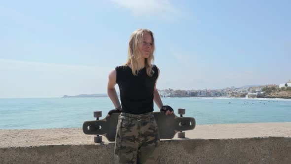 Beautiful and Style Young Girl Posing with a Skateboard at Seafront alt