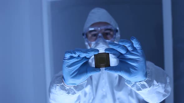 Man in clean room holds up computer cpu microchip alt