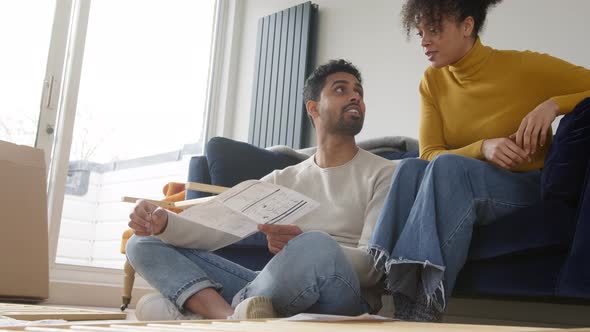 Young Couple In Lounge At Home Arguing Whilst Reading Instructions For Flat Pack Furniture Assembly alt